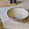Malia Bowl - Cream by Nkuku styled in a table setting, showing the everyday bowl shape, neutral cream glaze and relaxed stoneware finish.