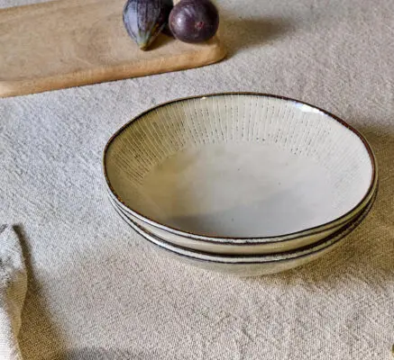 Malia Bowl - Cream by Nkuku styled in a table setting, showing the everyday bowl shape, neutral cream glaze and relaxed stoneware finish.