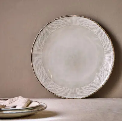 Malia Dinner Plate - Cream by Nkuku, a 28cm cream stoneware dinner plate with a shallow rounded shape, soft reactive glaze and hand-painted rim detail.