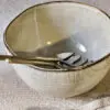 Malia Serving Bowl - Cream by Nkuku styled on a table, showing the generous serving bowl shape, cream glazed finish and relaxed stoneware tableware setting.