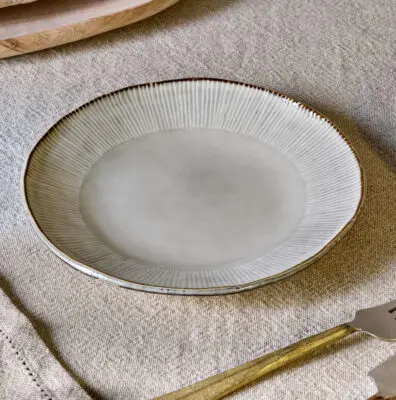 Malia Side Plate - Cream by Nkuku, a 22.5cm cream stoneware side plate with a shallow organic shape, soft reactive glaze and hand-painted rim detail.