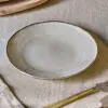 Malia Side Plate - Cream by Nkuku styled in a table setting, showing the 22.5cm plate size, neutral cream glaze and relaxed stoneware finish.