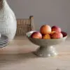 Valinha Earthenware Footed Bowl - Grey by Nkuku, showing the wide shallow bowl shape, raised footed base, textured spiral pattern and layered grey glaze.