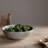Valinha Earthenware Serving Bowl - Grey by Nkuku styled on a table, showing the generous serving bowl shape, rustic grey glaze and textured artisan finish.
