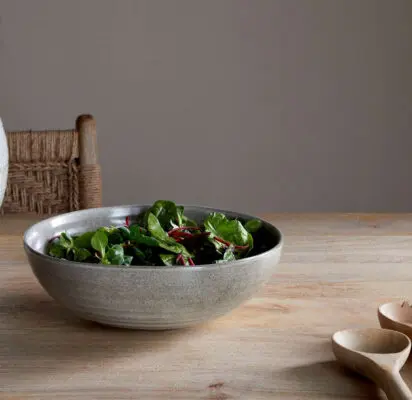 Valinha Earthenware Serving Bowl - Grey by Nkuku styled on a table, showing the generous serving bowl shape, rustic grey glaze and textured artisan finish.