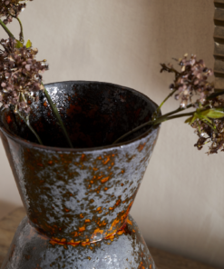 Brija Vase in Brown by Nkuku styled with flowers, closeup featuring a rich reactive glaze and softly textured finish.