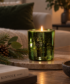 Enchanted Forest Luxury Candle in emerald electroplated glass lit on a coffee table with subtle pine and greenery styling.