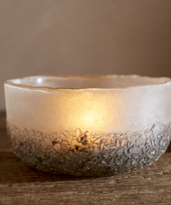 Close up of Riyara Recycled Glass Tealights in Silver Sparkle by Nkuku lit with candles, creating a soft warm glow through the textured glass.