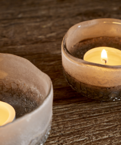 Close Up Riyara Recycled Glass Tealights in Silver Sparkle by Nkuku lit with candles, creating a soft warm glow through the textured glass.