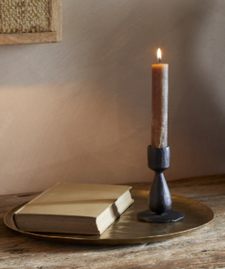 Suba Candle Holder in Black by Nkuku styled with a lit ester & erik cylindrical candle, creating a warm atmospheric glow.