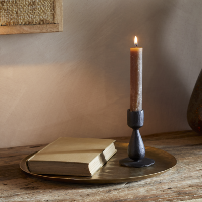 Suba Candle Holder in Black by Nkuku styled with a lit ester & erik cylindrical candle, creating a warm atmospheric glow.