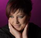 A woman with short hair and wearing an engagement ring.