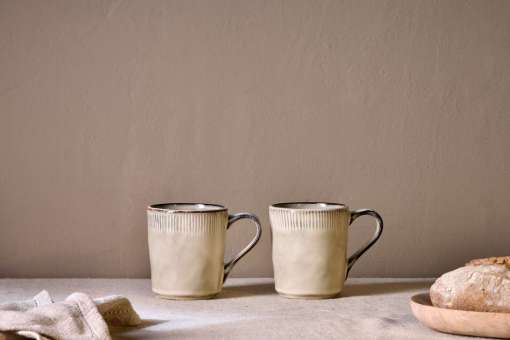 Malia Mug - Cream Set of 2 by Nkuku styled for tea or coffee, showing the rounded mug shape, warm cream glaze and relaxed stoneware finish.