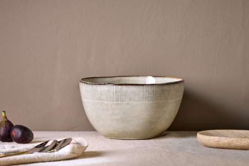 Malia Serving Bowl - Cream by Nkuku styled on a table, showing the generous serving bowl shape, cream glazed finish and relaxed stoneware tableware setting.