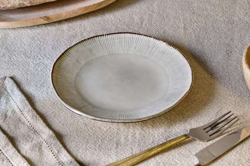 Malia Side Plate - Cream by Nkuku styled in a table setting, showing the 22.5cm plate size, neutral cream glaze and relaxed stoneware finish.