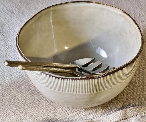 Malia Serving Bowl - Cream by Nkuku styled on a table, showing the generous serving bowl shape, cream glazed finish and relaxed stoneware tableware setting.