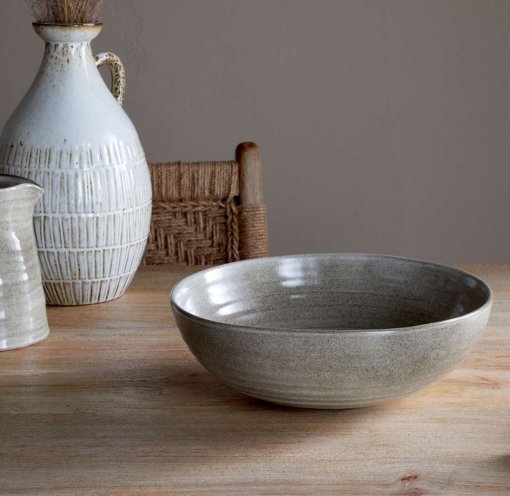 Valinha Earthenware Serving Bowl - Grey by Nkuku styled on a table, showing the generous serving bowl shape, rustic grey glaze and textured artisan finish.