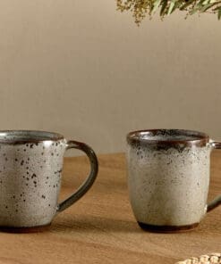 Cam Large Mug - Mocha Set of 2 by Nkuku, showing a matching pair of 350ml ceramic mugs with individual reactive glaze patterns and handcrafted character.