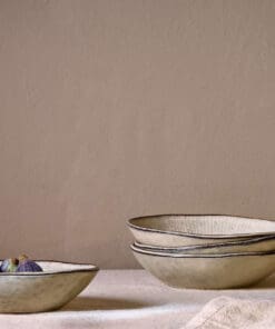Malia Bowl - Cream by Nkuku styled in a table setting, showing the everyday bowl shape, neutral cream glaze and relaxed stoneware finish.