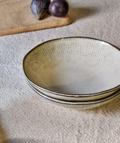 Malia Bowl - Cream by Nkuku styled in a table setting, showing the everyday bowl shape, neutral cream glaze and relaxed stoneware finish.