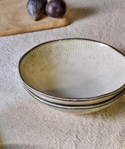 Malia Bowl - Cream by Nkuku, a 615ml cream stoneware bowl with a low rounded shape, soft reactive glaze and hand-painted line detail around the rim.