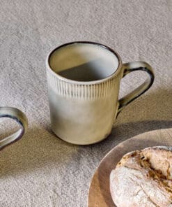 Malia Mug - Cream Set of 2 by Nkuku, showing two 380ml cream stoneware mugs with organic shapes, soft reactive glaze and hand-painted rim detail.