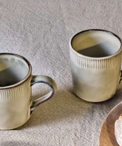 Close-up of the Malia Mug - Cream by Nkuku, showing the cream stoneware surface, textured handle, subtle glaze variation and fine hand-painted line detail.