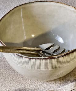 Malia Serving Bowl - Cream by Nkuku styled on a table, showing the generous serving bowl shape, cream glazed finish and relaxed stoneware tableware setting.