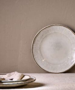 Malia Side Plate - Cream by Nkuku, a 22.5cm cream stoneware side plate with a shallow organic shape, soft reactive glaze and hand-painted rim detail.