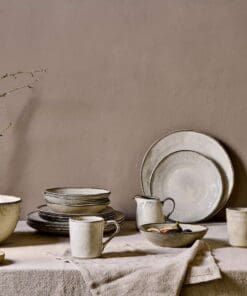 Malia Jug - Cream - Small by Nkuku styled on a table, ideal for serving milk, cream, sauces or dressings with relaxed neutral tableware.