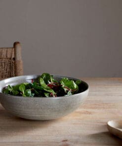 Valinha Earthenware Serving Bowl - Grey by Nkuku styled on a table, showing the generous serving bowl shape, rustic grey glaze and textured artisan finish.