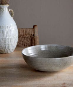 Valinha Earthenware Serving Bowl - Grey by Nkuku styled on a table, showing the generous serving bowl shape, rustic grey glaze and textured artisan finish.