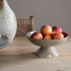 Valinha Earthenware Footed Bowl - Grey by Nkuku, showing the wide shallow bowl shape, raised footed base, textured spiral pattern and layered grey glaze.