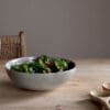 Valinha Earthenware Serving Bowl - Grey by Nkuku styled on a table, showing the generous serving bowl shape, rustic grey glaze and textured artisan finish.