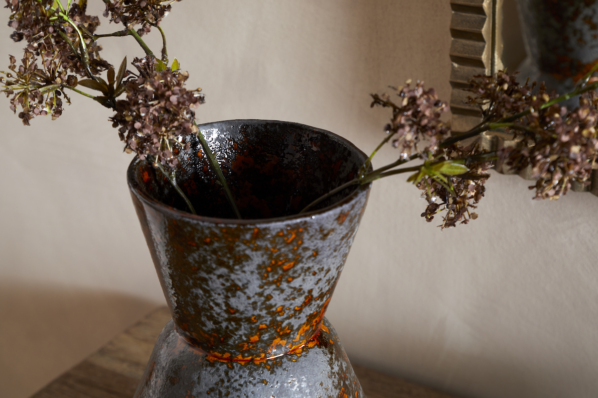 Brija Vase in Brown by Nkuku styled with flowers, closeup featuring a rich reactive glaze and softly textured finish.