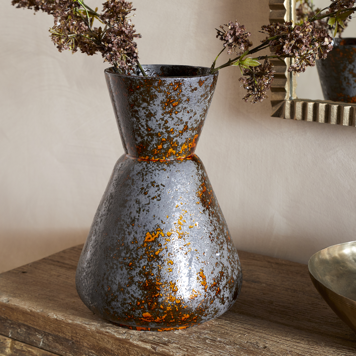 Brija Vase in Brown by Nkuku styled with flowers, featuring a rich reactive glaze and softly textured finish.