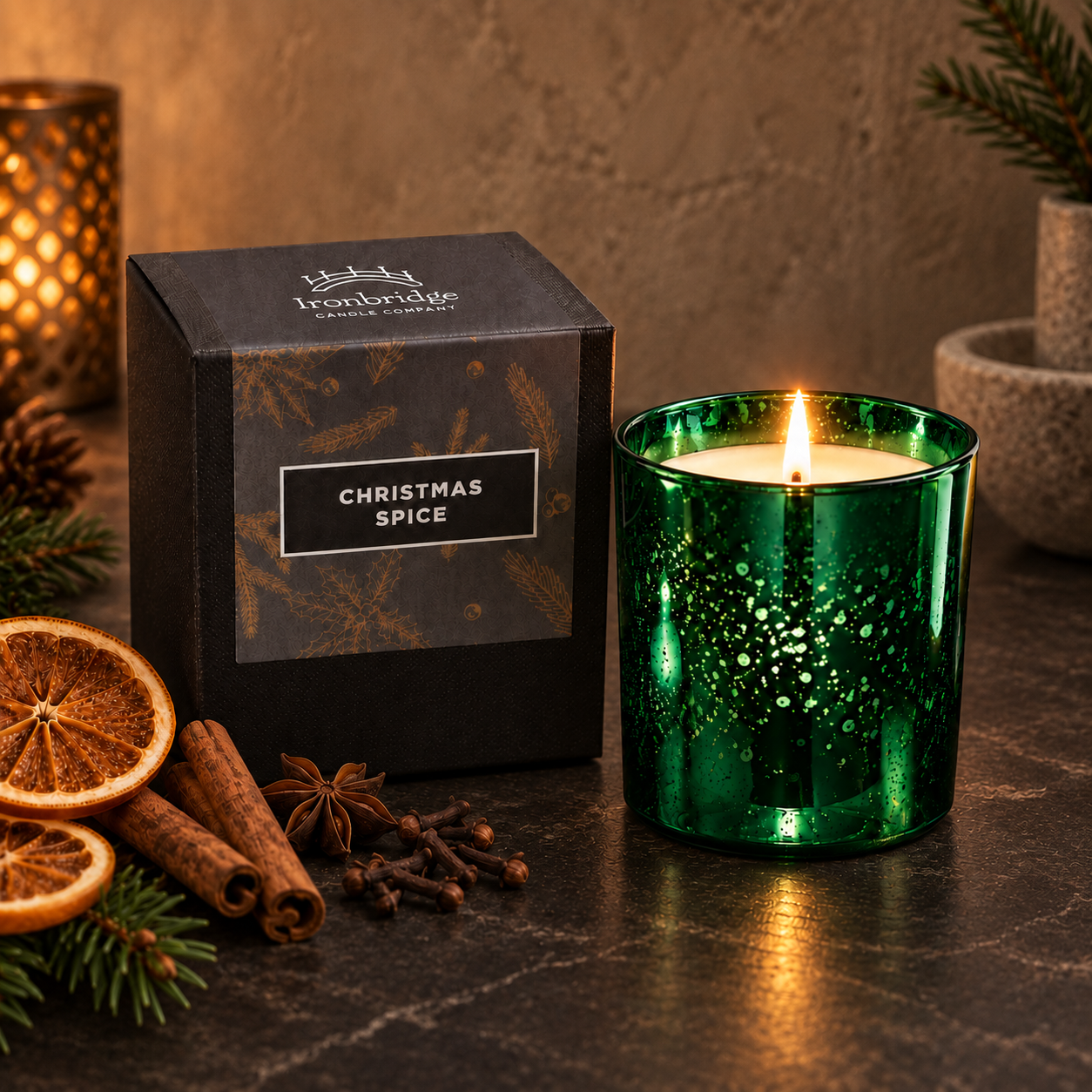 Christmas Spice Luxury Candle in emerald electroplated glass with branded box, styled with festive spices and greenery on a warm neutral backdrop.