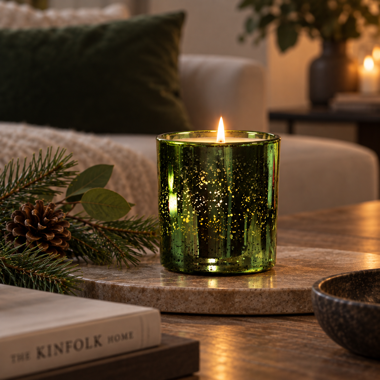 Enchanted Forest Luxury Candle in emerald electroplated glass lit on a coffee table with subtle pine and greenery styling.