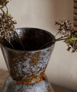 Brija Vase in Brown by Nkuku styled with flowers, closeup featuring a rich reactive glaze and softly textured finish.