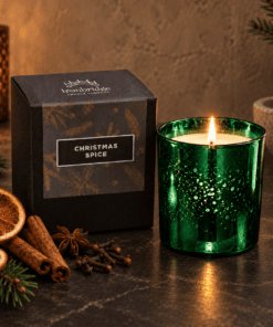 Christmas Spice Luxury Candle in emerald electroplated glass with branded box, styled with festive spices and greenery on a warm neutral backdrop.