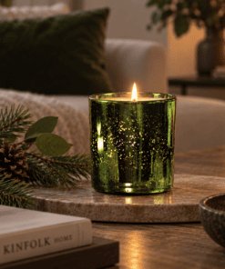 Enchanted Forest Luxury Candle in emerald electroplated glass lit on a coffee table with subtle pine and greenery styling.