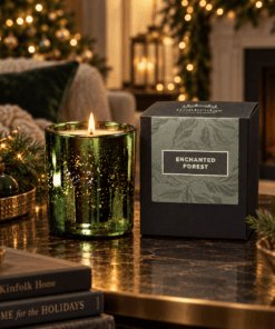 Enchanted Forest Luxury Candle in emerald electroplated glass lit beside its branded box in a warm festive living room.