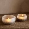 Riyara Recycled Glass Tealights in Silver Sparkle by Nkuku lit with candles, creating a soft warm glow through the textured glass.