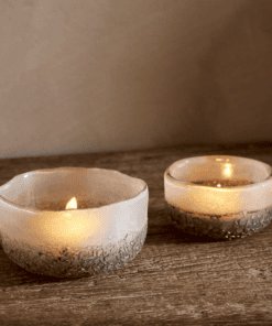 Riyara Recycled Glass Tealights in Silver Sparkle by Nkuku lit with candles, creating a soft warm glow through the textured glass.