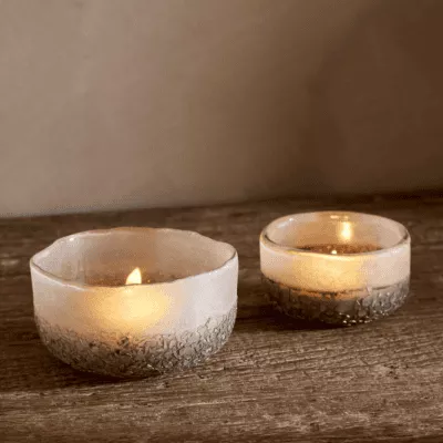 Riyara Recycled Glass Tealights in Silver Sparkle by Nkuku lit with candles, creating a soft warm glow through the textured glass.