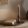 Suba Candle Holder in Black by Nkuku styled with a lit ester & erik cylindrical candle, creating a warm atmospheric glow.