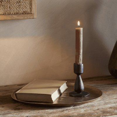 Suba Candle Holder in Black by Nkuku styled with a lit ester & erik cylindrical candle, creating a warm atmospheric glow.