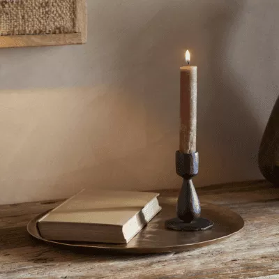 Suba Candle Holder in Black by Nkuku styled with a lit ester & erik cylindrical candle, creating a warm atmospheric glow.