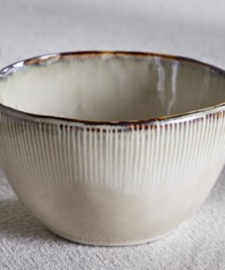 Nkuku Malia Breakfast Bowl in Cream, featuring a softly curved shape, fine vertical ribbed detailing, a warm cream glaze and a contrasting hand-finished brown rim.